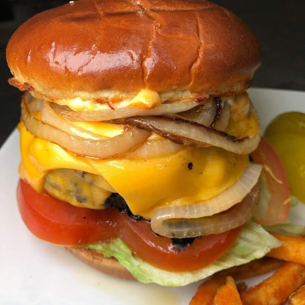 A large cheeseburger with tomatoes, onions and cheese.